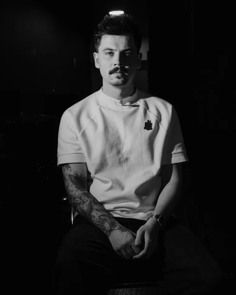 Levi Moreira sentado, de camiseta branca, em foto preto e branco